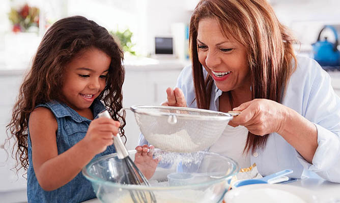 Woman and granddaughter in the kitchen baking; heart scan promotion.