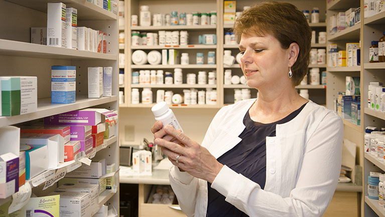 VIMCare pharmacist reading label on bottle of medicine