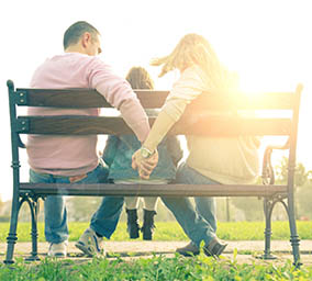 Family sitting on bench with child.